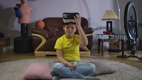 Porträt-von-männlichen-kaukasischen-Teenager-auf-VR-Headset-und-mit-Fernbedienung,-um-das-Spiel-einzuschalten.-Kind-versucht-auf-Gerät-zu-Hause.-Virtuelles-Headset,-Online-Spiele,-3D-Realität.-Kino-4k-ProRes-HQ.