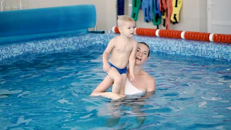 Schwimmbad.-Mama-bringt-einem-kleinen-Kind-das-Schwimmen-im-Pool-bei.