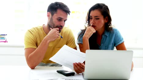 Worried-couple-calculating-their-bills-with-laptop-in-the-kitchen