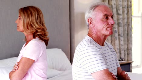 Upset-senior-couple-sitting-back-to-back-on-bed