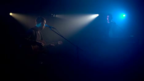 Two-musicians-sing-into-the-microphone