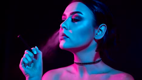 Hermosa-mujer-morena-fumar-cigarrillo-electrónico-en-luz-de-neón-color