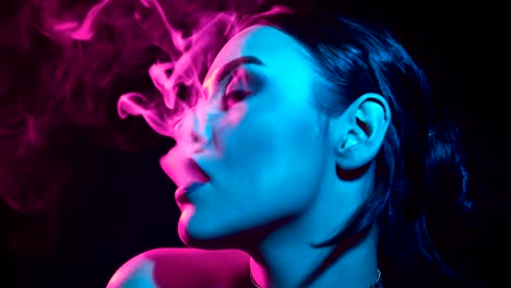 Gorgeous-brunette-woman-smoking-electronic-cigarette-in-neon-color-light