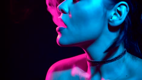 Gorgeous-brunette-woman-smoking-electronic-cigarette-in-neon-color-light