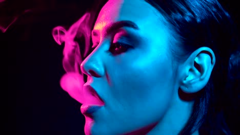 Gorgeous-brunette-woman-smoking-electronic-cigarette-in-neon-color-light