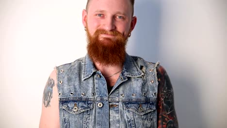 modern-youth.-a-cheerful-portrait-of-a-kindly-smiling-biker-with-tattoos-and-a-stylish-beard-and-mustache-in-a-denim-vest.