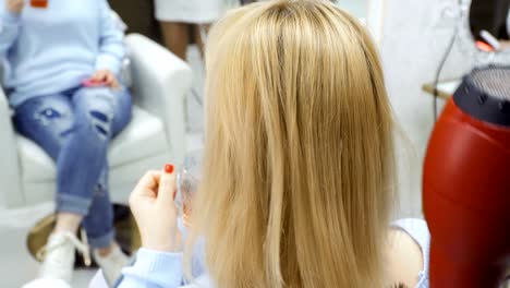 Hairdresser-dries-female-hair-with-hairdryer-and-brush