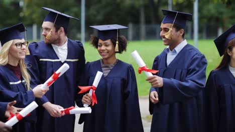 glückliche-Schüler-in-Mörtel-Boards-mit-Diplomen