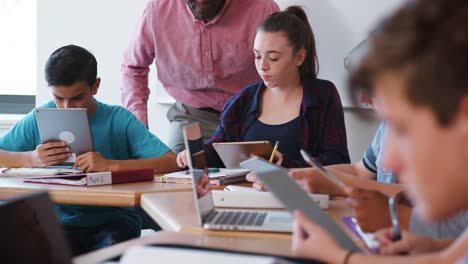 Female-High-School-Student-Receiving-Individual-Attention-From-Teacher-In-Class