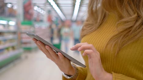 Kundin-mit-einem-digitalen-Tablet-im-Supermarkt