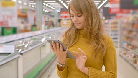 Frauen-im-Supermarkt-einkaufen-und-mit-mobilen-apps-auf-ihrem-tablet