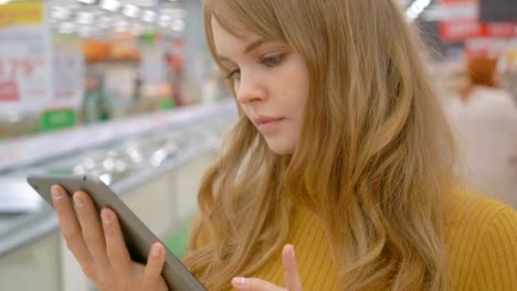 Mujer-cliente-utilizando-una-tableta-digital-en-el-supermercado