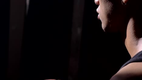 African-basketball-player-with-pierced-ear-sitting-and-waiting-for-game-to-start,-playing-with-ball