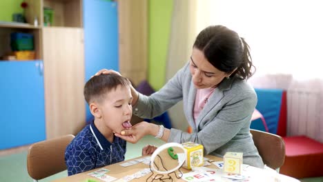 Eine-attraktive-Frau-Logopädin-lehrt-eine-Vorschule-junge-bei-einer-Sprachtherapie-session