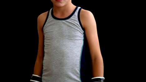 A-young-boxer-in-a-gray-sports-shirt-stands-on-a-dark-background,-he-holds-his-hands-in-gloves-on-the-body,-the-boy's-head-and-legs---off-screen