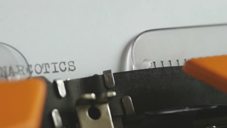 Close-up-footage-of-a-person-writing-NARCOTICS-on-an-old-typewriter
