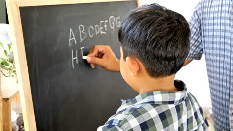 Father-teaches-children-boy-to-writing-the-chalkboard.-Education-concept.