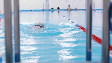 Schwimmkurse-für-Kinder-in-den-Pool---schönes-hellhäutige-Mädchen-im-Wasser-schwimmt