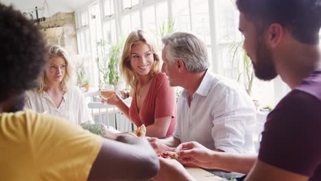 A-multi-ethnic,-mixed-age-group-of-adult-friends-eating-tapas-together-at-a-table-in-a-restaurant,-close-up,-selective-focus