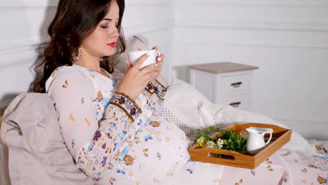 Relaxing-pregnant-woman-drinking-healthy-tea-in-bed