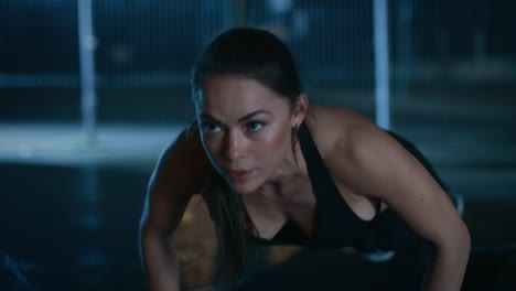 Exhausted-Beautiful-Sporty-Fitness-Girl-Doing-Push-Up-Exercises.-She-is-Doing-a-Workout-in-a-Fenced-Outdoor-Basketball-Court.-Night-Footage-After-Rain-in-a-Residential-Neighborhood-Area.