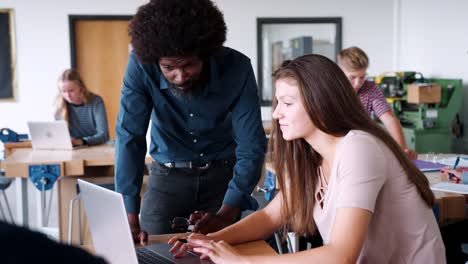 Profesor-hablando-con-estudiante-de-secundaria-de-la-mujer-sentada-en-el-Banco-de-trabajo-usando-Laptop-en-diseño-y-tecnología-lección