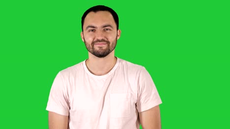 Young-happy-man-in-t-shirt-smiling-at-camera-and-walking-on-a-Green-Screen,-Chroma-Key