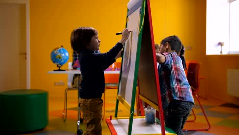 Creative-multicultural-boys-drawing-on-easel-board