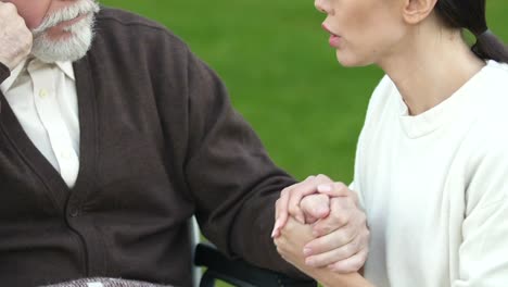 Desperate-daughter-saying-goodbye-to-terminally-ill-father-in-wheelchair-closeup