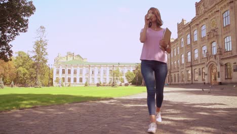 young-woman-holding-notebook-walks-outdoors