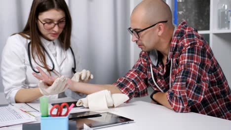 Médico-examina-la-muñeca-dañada-de-un-hombre-paciente.