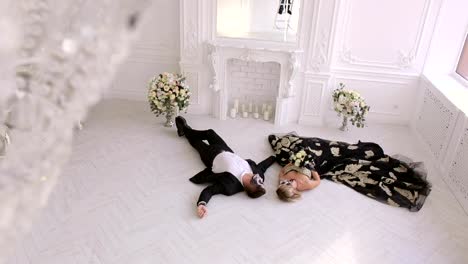 A-couple-with-makeup-on-their-face-lie-on-the-floor-in-a-vintage-room.-Halloween