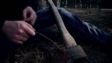 Mentally-ill-man-sits-and-picks-up-dried-blood-on-murder-weapon-in-forest