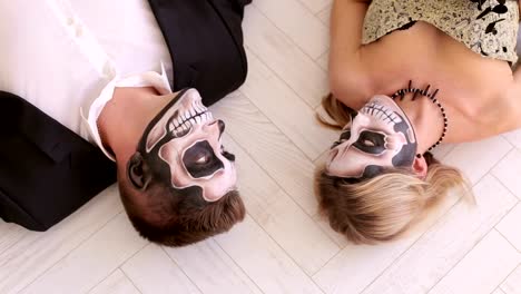 A-couple-in-carnival-costumes-lie-on-the-floor-on-a-white-floor.-Halloween-party