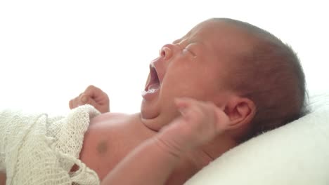 4K-Video-Selective-focus-real-time-dolly-shot-of-newborn-baby-girl-laying-down-on-white-bed-and-crying