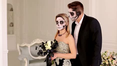 Pareja-con-maquillaje-de-calavera-de-Halloween-en-un-vestido-en-una-habitación-con-interior-vintage.