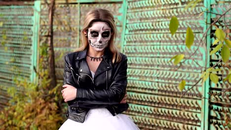 Mädchen-in-einer-Lederjacke-mit-Make-up-für-Halloween-auf-dem-Hintergrund-eines-alten-Zauns