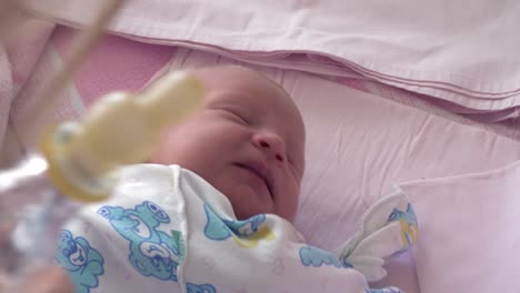 Mutter-gibt-Flasche-mit-Wasser-zu-verschlafenem-Neugeborenen