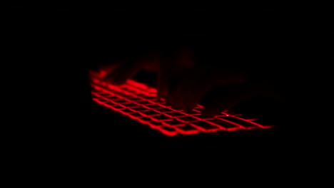 Hacker-typing-code-on-laptop-at-night