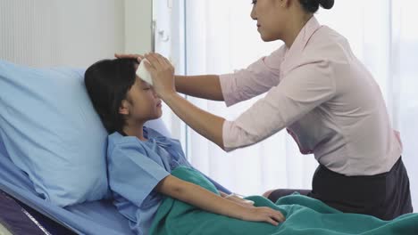 Asiatische-Mutter-reiben-den-Körper-Patient-kleines-Mädchen-für-die-Temperatur-und-körperliche-Untersuchung-im-Krankenhaus-zu-reduzieren.-Konzept-der-Familie,-Medizin,-Gesundheitswesen-und-Technologie.