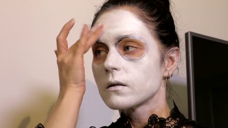 Frau-wenden-weißes-Make-up-auf-ihr-Gesicht.-Halloween-Konzept