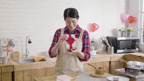 asian-woman-opening-gift-box-in-kitchen