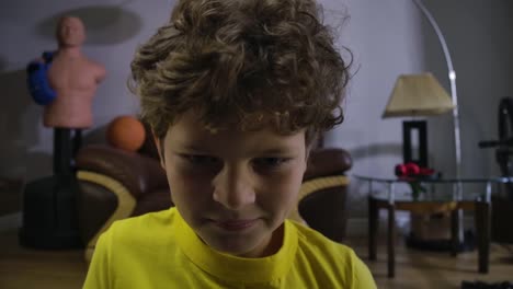 Face-of-cute-Caucasian-boy-with-tired-eyes-getting-angry-as-loosing-in-video-game.-Curly-haired-teenager-in-yellow-T-shirt-using-smartphone-to-play.-Gaming,-technologies.-Cinema-4k-ProRes-HQ.