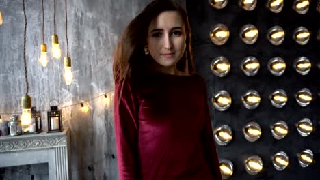 Young-woman-in-dress-and-beautiful-face-on-a-background-of-wall-with-powerful-lamps