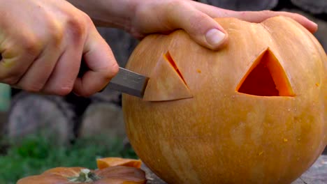 Man-carves-from-a-pumpkin-Jack-o'-lantern-in-the-backyard-on-a-tree-stump