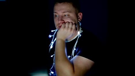 Sad-young-man-with-christmas-garland-using-computer