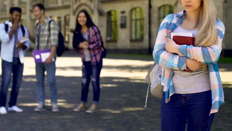 Estudiantes-riendo-y-señalando-a-la-niña-triste-solitaria-de-pie-a-un-lado,-cruel-bulling