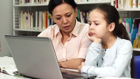 Mujer-asiática-madura-ayudando-a-su-hija-cansada-con-la-tarea