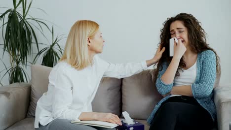 Female-experienced-psychologist-talking-and-calm-down-depressed-crying-woman-patient-during-psychotherapy-session