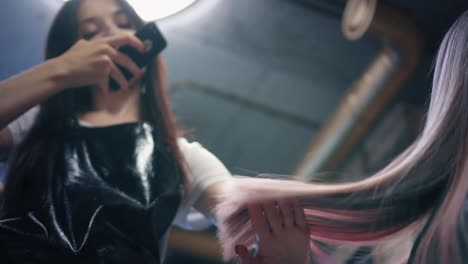 Hairdresser-take-a-photo-of-woman's-long-coloured-hair-on-smartphone-in-hair-salon.-Hairdresser-admires-her-work-and-shows-strands-of-dyed-hair.-Down-angle.-Slow-mo